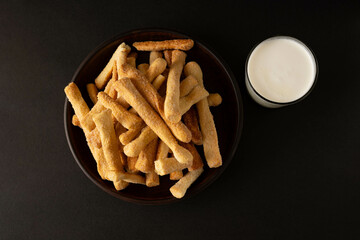 Cookies and a glass of milk on a dark background.