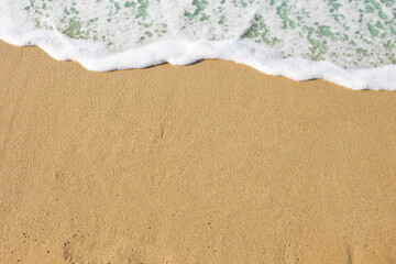 Fototapeta na wymiar Sea beach with waves. Sand beach texture, top view. White foam wave, sandy seashore. Summer vacation background.