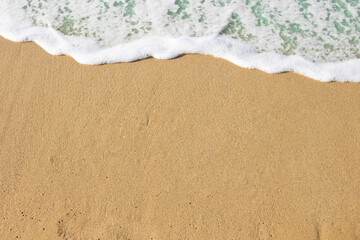 Sea beach with waves. Sand beach texture, top view. White foam wave, sandy seashore. Summer vacation background.