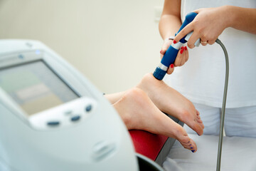 Doctor neurologist using shockwave to relieve pain heel spur. Close up view. Extracorporeal...