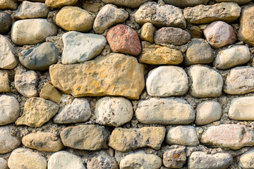 A field stone wall with brown, red and white stones with fossils.
