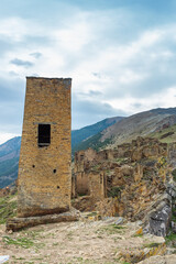 Fototapeta na wymiar Tower and old houses of the abandoned village of Goor, Dagestan, Russia. Stone town on the rocks. Ancient stone city in the mountains against the blue sky