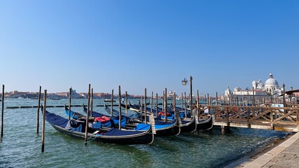 Fototapeta na wymiar Gondolas moored by Piazza San Marco with San Giorgio di Maggiore church in Venice, Italy