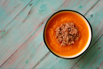 pumpkin soup puree in a round plate with tuna is on a blue wooden table. view from above. diet