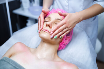 Obraz na płótnie Canvas Cosmetologist applies cream on the skin of the client
