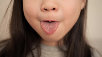 Little girl sticking out her tongue and teeth. Close-up of a girl face smile. Child shows mouth to the doctor. Health concept.