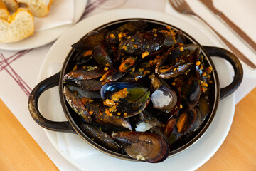 Delicious dish of grilled mussels with minced meat in a frying pan