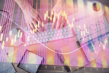 Multi exposure of man's hands typing over computer keyboard and forex graph hologram drawing. Top...