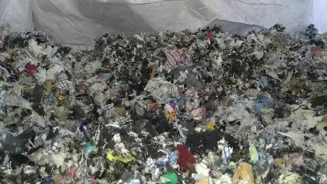 Textile waste being recycled. Shredded Textiles fall. 30fps Concept recycling industry and ecology