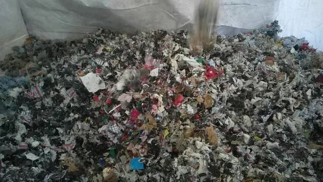 Crush Textile waste falling to a big bag. 30fps Concept recycling industry. Closeup. Textiles are not recycled properly nowadays. High quality footage
