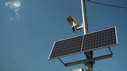 Photo camera monitors the rules of the road. Camera on a pole with a solar panel against the sky.