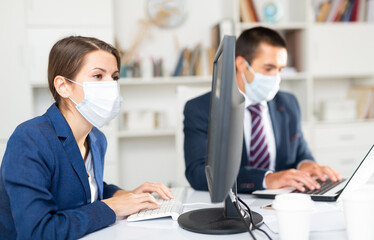 Director in protective medical mask gives instructions to secretary in office