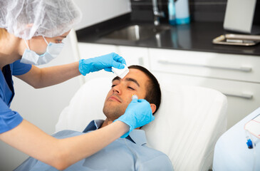 Portrait of male patient during cosmetology procedure in beauty clinic, getting carbon dioxide injections for face skin rejuvenation
