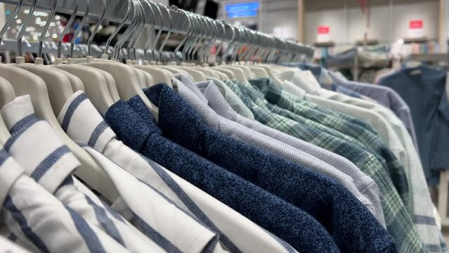 Men's shirts hang in rows on hangers in a clothing store. Close-up