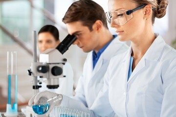 Scientists with microscopes working with tests in laboratory