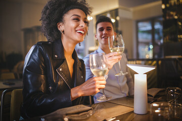 Multiethnic couple talking at restaurant drinking white wine