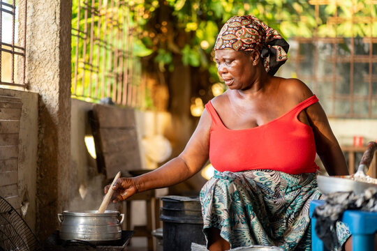 image of african woman with a cooking pot- black mother preparing local dish- food concept