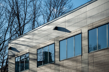 Fototapeta premium The exterior wall of a contemporary commercial style building with aluminum metal composite panels and glass windows. The futuristic building has engineered diagonal cladding steel frame panels.