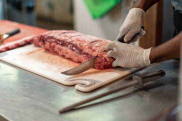 A close up of a large prime rib roast is sitting on a brown plastic cutting board. The meat has...