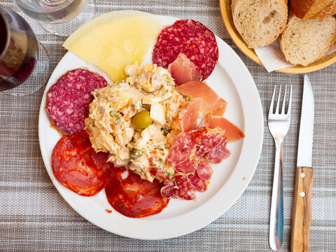 Traditional Spanish appetizer Entremeses, cold cuts of various sausages, jamon and cheese slices served with Russian salad