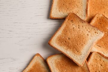 Slices of delicious toasted bread on white wooden table, top view. Space for text