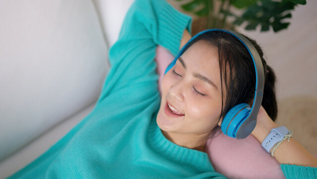 Asia teen girl people enjoy break time self relax happy joy good song on live stream online radio app lying down rest sleep at cozy sofa. Youth fun hobby indoor lazy zen life smile napping at home.