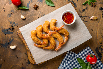 fried tempura shrimps on the board with sweet chili sauce on wooden table top view