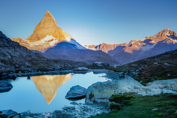Naklejka premium Matterhorn iconic mountain and lake relfection at peaceful sunrise, Swiss Alps