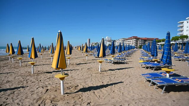 Deckchairs and parasols on sandy beach near the sea. Exotic beach in summer. Vacation, travel and tourism concept. Lido di Jesolo, Italy. 
