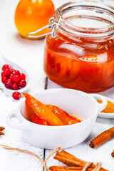 Persimmon jam in glass jar on wooden  background. Close up