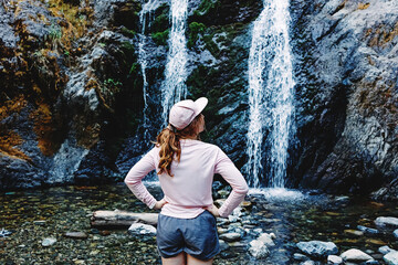 Young woman enjoying time near the waterfall after the hike