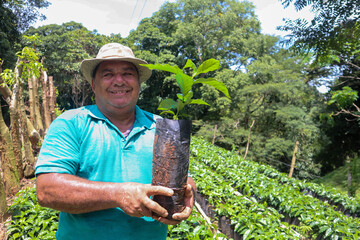 Happy farmer holding a coffee plant in the field