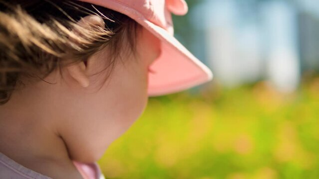 Face close-up of Thursty Little Girl Picking Up Water Bottle And Drink At The Flowering Field - slow motion