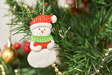 Close-up view of a decorated Christmas tree, friendly snowman hanging on a branch. Composition with copy space.