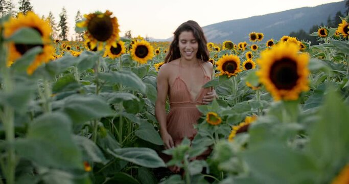 Beautiful carefree joyful female in sundress gallops through sunflower field
