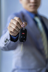 Holding car keys Asian businessman in classic gray shirt suit isolated on gray wall background studio photo. career success wealthy business business idea