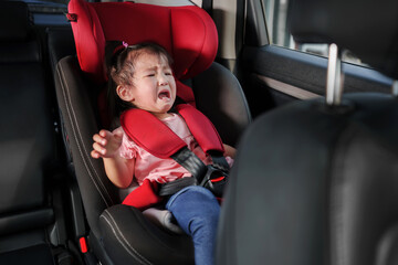 crying toddler girl sitting in car seat