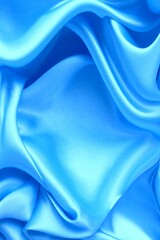 Beautiful light blue material folded into folds. Silk, satin. Solid background.