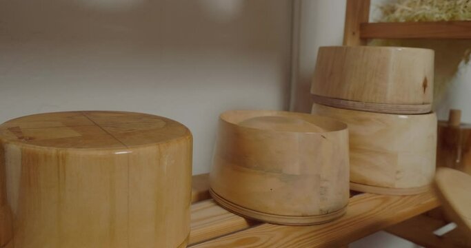 Woman arranges wooden molds for making hats in rows on shelf