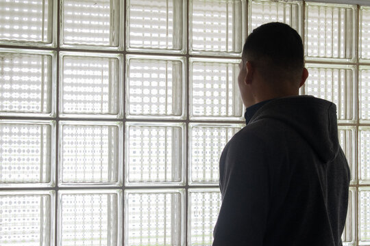 Joven viendo por una ventana de bloques traslucidos