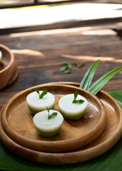 Talam Cake or in indonesia called kue talam with pandan leaves serves on wooden plate, selective focus image and blurred background.