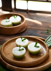 Talam Cake or in indonesia called kue talam with pandan leaves serves on wooden plate, selective focus image and blurred background.