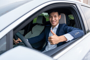 A businessman thumbs up while sitting in a new electric car with a happy smile. EV Car. EV vehicle. Concept of green energy and reduce CO2 emission.