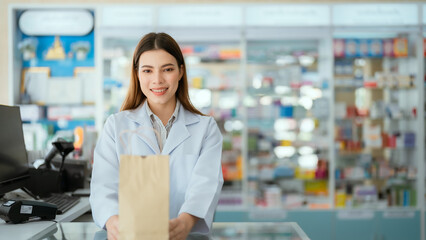 A young pharmacist presents a paper bag containing medicines to sell in a general pharmacy.