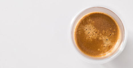 Freshly brewed coffee in a glass cup on a white background, top view, central composition? banner