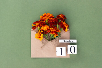 October 10. Bouquet of orange flower in craft envelope and calendar date on green background....