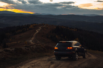 Car is going down offroad in mountains during autumn evening