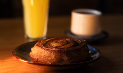 rol de canela con café de fondo y jugo de naranja 