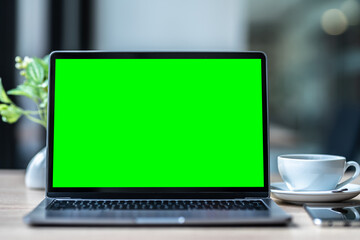 Mockup of laptop computer with empty screen with coffee cup and smartphone on table of the coffee shop background,Green screen - Powered by Adobe