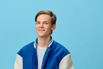 portrait of a handsome pleasantly smiling young man student in a trendy jacket on a blue background